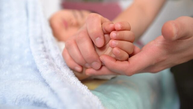 Mother baby sniffing and kissing. Mother sniffs and kisses her sleeping baby's hand. Sweet hands of innocent baby.