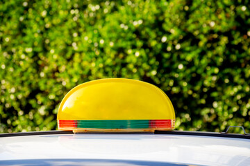 Yellow Taxi Sign without an inscription on the roof of a yellow car on a Summer Day against a...