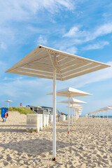 Wooden white umbrellas from the sun on the sandy beach.