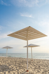 Wooden white umbrellas from the sun on the sandy beach.