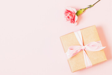 Gift box and fresh flower on light pink background with empty place for design, flat lay