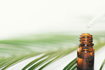 Closeup essential oil drops into bottle from pipette