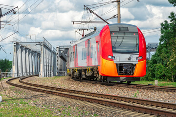 Obraz premium A new electric train passes over the bridge.