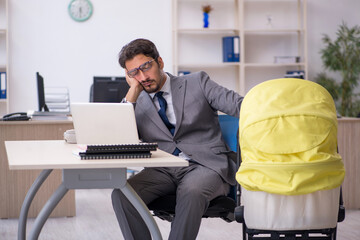 Young male employee looking after new born at workplace