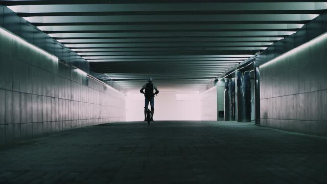 A man rides a mono wheel along an underground passage. Eco-friendly individual transport. Fast movement around the city. Mobile portable vehicle.