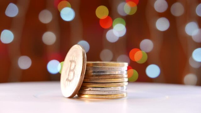Bitcoin coin with Christmas holiday season decoration, coin stack and colorful festive bokeh string light in background, selective focus