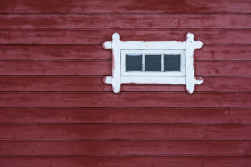old routed window on a red wooden wall