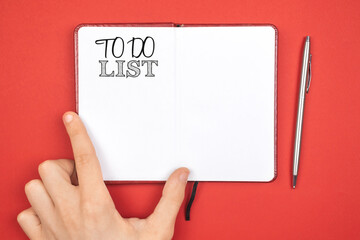 Obraz premium Notebook with to do list. Planning for new year concept. Red background, silver pen, copy space and top view photo