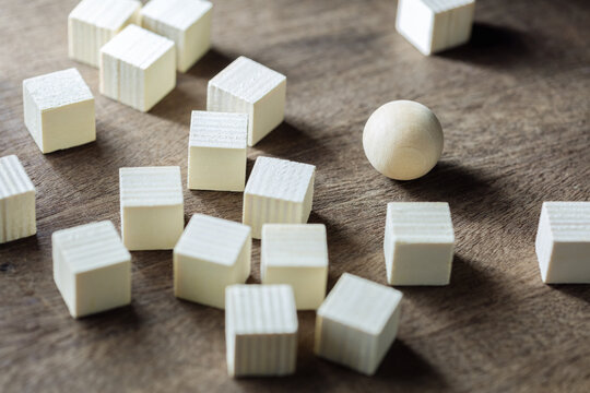 Round Wood Ball Among The Group Of Many Wood Cubes On The Table, Find Your Own Position And Behave Yourself