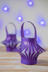 Home decoration, purple paper lanterns and purple garland on a wooden background. Children's creativity, craft, DIY.