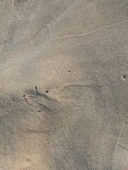 Wet sand with delicate mountains, holes and lines created by ocean waves that resemble aerial landscapes. Illustration concept for decoration.