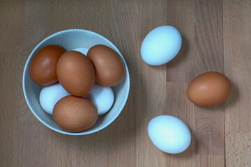 several fresh chicken eggs in a ceramic cup on a wooden background. Healthy eating concept