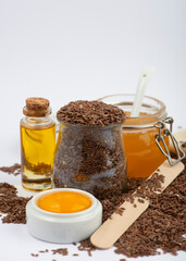 Brown flax seeds, linseeds oil, egg and honey on white background. Home made cosmetics ingredients.