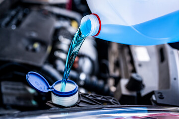Pouring antifreeze. Filling a windshield washer tank with an antifreeze in winter cold weather... - obrazy, fototapety, plakaty