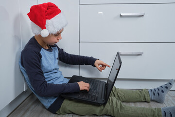 chłopka w czapce świętego mikołaja korzysta z laptopa 