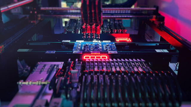 Digital technologies SMT automation industry. Red neon lights illuminate Chip Components for automation test. SMT Concept. Robotic Manipulator arranges electronic microcomponents on a computer board.