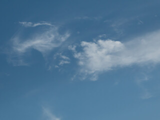 White cloud looking like cotton candy floats in the blue sky like a hand.