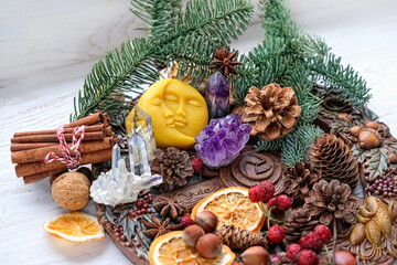 Wiccan altar for Yule sabbat. Sun-moon amulet, wheel of the year, gemstones, nuts, cones, dry orange slices. Esoteric Ritual for Christmas, Yule, Winter Solstice - obrazy, fototapety, plakaty