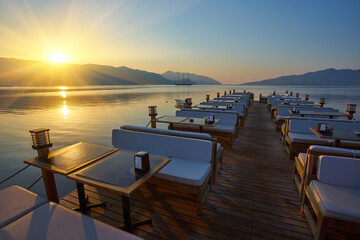 Obraz premium Beach cafe at dawn. Empty tables in a cafe, a sunny morning on the beach.