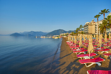 sandy beach without people and with sun loungers, umbrellas, palm trees, Marmaris