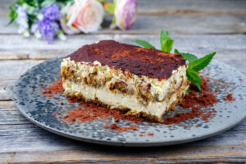 Modern style traditional Italian tiramisu served as close-up on a Nordic design plate on a wooden board