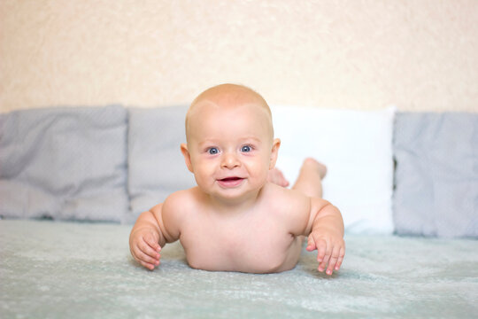 Naked smiling baby boy lying on blue background. Picture with focus picked and depth of field
