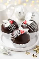 Hot chocolate bombs with marshmallows inside on a  white plate. Christmas festive dessert for...