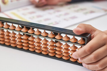 Doing mental math or mental arithmetic. Hand of little boy using abacus for calculating. Learning to use abacus on mental math courses. A kid doing math at home with abacus