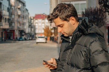 Obraz premium man looking at mobile phone or cell phone on the street