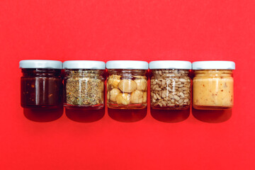Top view package gift or present with glass canned and preserving jars container with uncooked beans, grains healthy food isolated on red background, Vegetarian dieting assorted legumes

