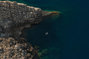 cliff-top view of a small bay with a boat on a sunny day