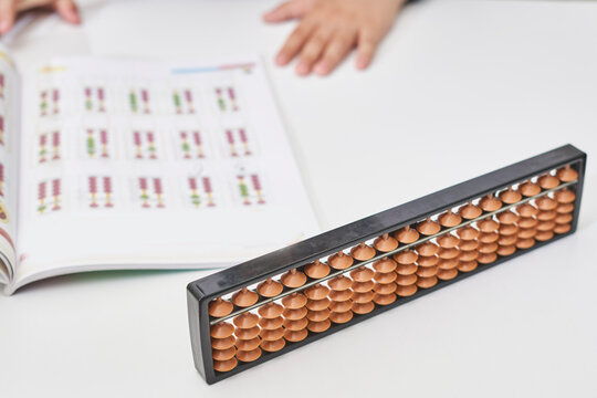 Doing mental math or mental arithmetic. Hand of little boy using abacus for calculating. Learning to use abacus on mental math courses. A kid doing math at home with abacus