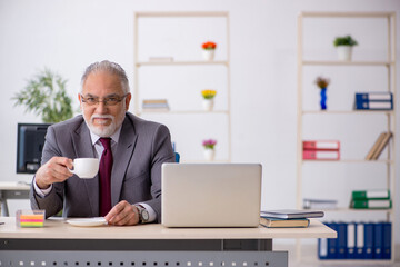 Fototapeta na wymiar Old male employee drinking coffee during break