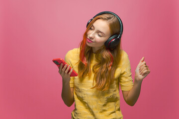 Modern young girl enjoy listening musical playlist with headphones closed eyes on pink background. Music app advertising