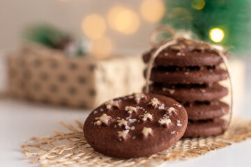 on the table is a stack of round chocolate Christmas cookies and glass of milk