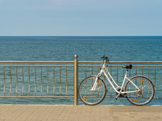 Fototapeta premium A lady's white bicycle standing at the railing against the background of the sea.