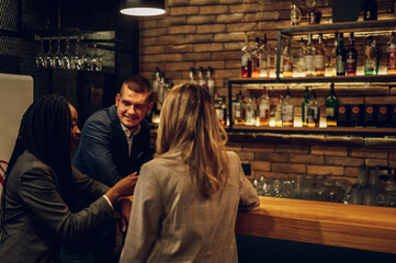 Cheerful colleagues drinking beer in the bar together after work and using a tablet