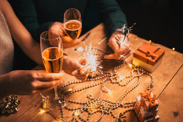 happy couple holding sparkles and champagne glasses New Year party