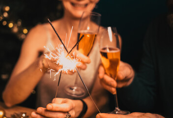 happy couple holding sparkles and champagne glasses New Year party