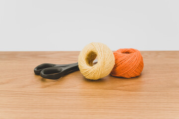 decorative rustic yellow orange yarn ball and scissors on a wooden background