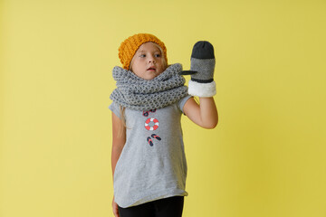 Adorable little girl in knitted hat standing in studio