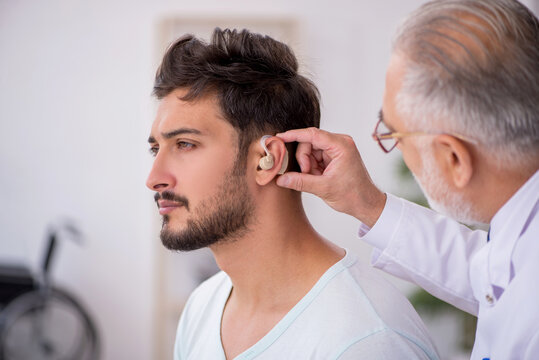 Young male patient with hearing problem visiting old doctor otor