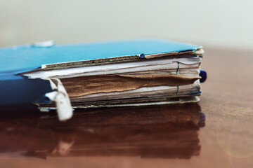 Ripped old paper notebook in blue cover lying on wooden table