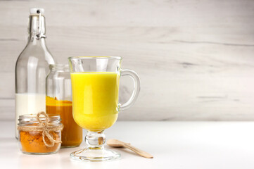 A glass of golden milk, turmeric beverage and ingredients