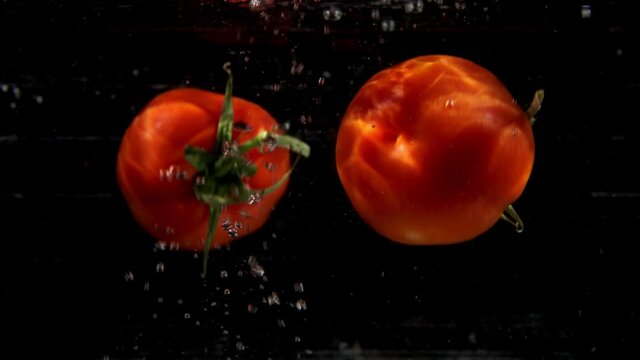 Tomatoes dropping in water - slow motion shot