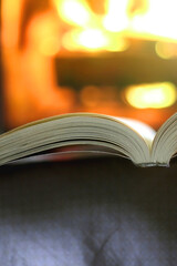 Open book in front of a fireplace. Selective focus.
