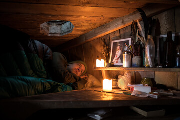 Young adult man sleeping in a small wooden cabin in Lofoten, Kvalvika beach, Norway