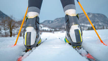 LOW ANGLE: Woman nordic skiing pushes off her poles and skis along two tracks.