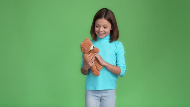 Schoolchild catch birthday gift bear cuddle isolated green color background 