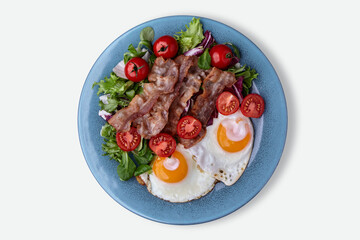 Fried eggs on blue plate with bacon, lettuce and cherry tomatoes